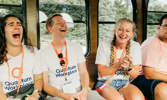 Three Quantum Workplace employees laughing on a trolley.