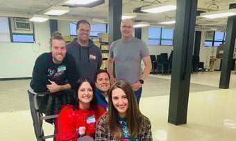 Six Quantum Workplace employees volunteering and posing with a flatbed cart.