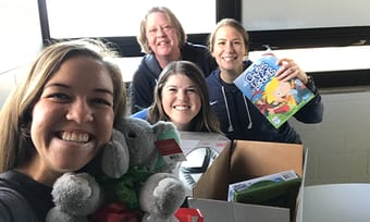 Four Quantum Workplace employees volunteering to package holiday gifts for children