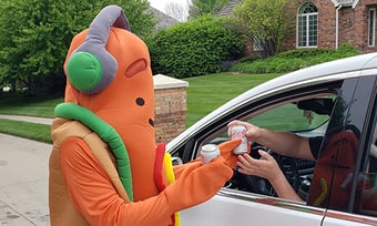 A Quantum Workplace employee dresses in a hot dog suite handing out hotdogs