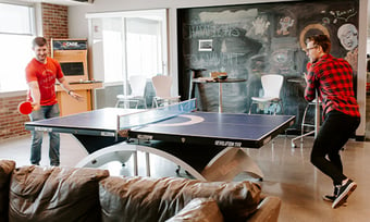 Two Quantum Workplace employees playing ping pong