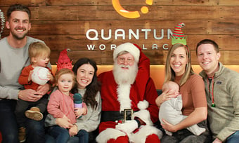Two Quantum Workplace employees and their spouses and kids with Santa