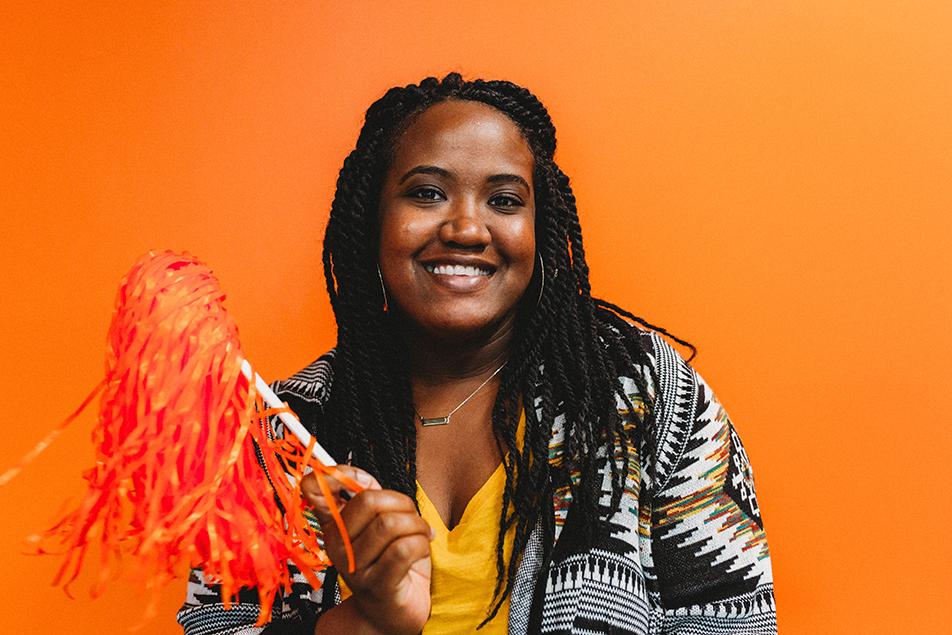 Quantum Workplace employee smiling and holding a pom pom