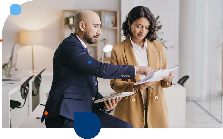 A leader and manager standing in an office looking at performance management research and trends.