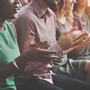 Row of people clapping with focus on to people